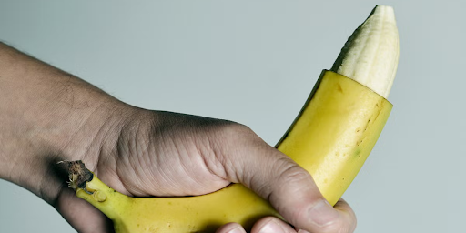 Image of banana with the top-most part skin being cut, resembling a circumcised penis.